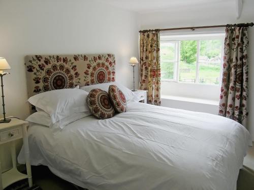 a bedroom with a white bed with pillows and a window at Mill Cottage in Rievaulx