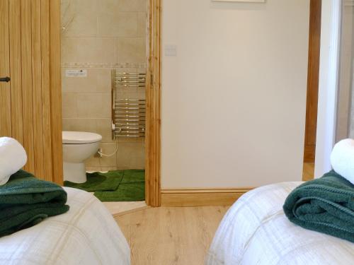 two beds in a room with a bathroom with a toilet at Reed Lodge in Littleport