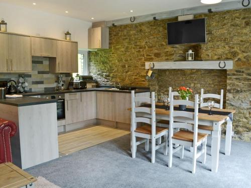 a kitchen with a table and chairs and a stone wall at Rosecraddoc Manor - Stable in Saint Cleer