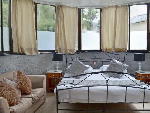 a bedroom with a bed and a couch and windows at Rosecraddoc Manor - Stable in Saint Cleer