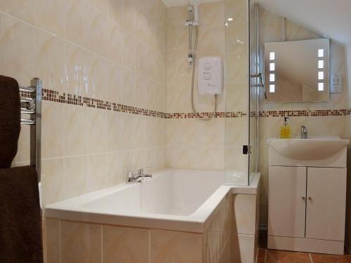 a bathroom with a tub and a sink and a shower at Nuthatch - 29363 in Ifton Heath