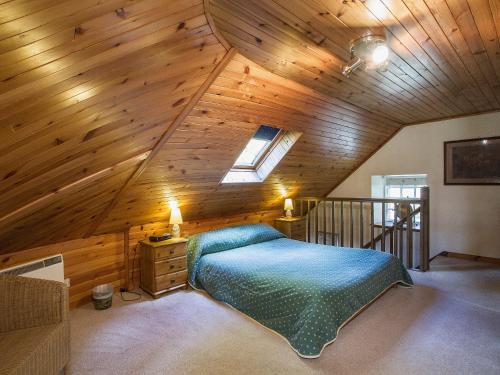 een slaapkamer op zolder met een bed en een houten plafond bij Tinkerbell in Balnaboth