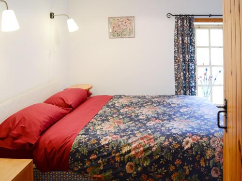 a bedroom with a bed with a floral bedspread at Stable Cottage in John O Groats