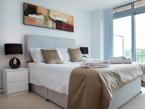 a bedroom with a bed with white sheets and a window at Fistral View - 3 Cribbar in Newquay