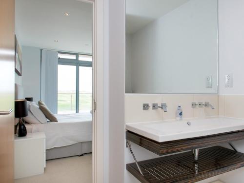 a white bathroom with a sink and a bed at Fistral View - 3 Cribbar in Newquay