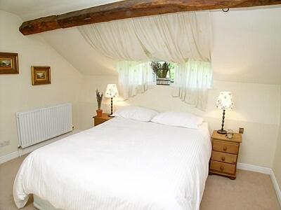 1 dormitorio con cama blanca y ventana en Wee Bridge Farm Cottage, en Mobberley
