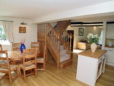 cocina y comedor con mesa y escalera en Wee Bridge Farm Cottage, en Mobberley