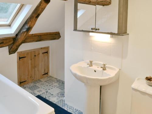 bagno bianco con lavandino e specchio di Dyes Cottage a Hindolveston