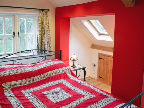 a red bedroom with a bed and a window at Dyes Cottage in Hindolveston