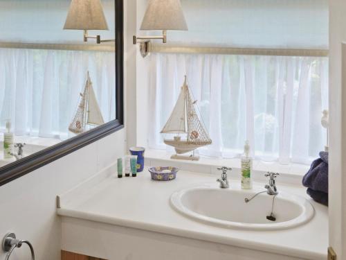 lavabo en el baño con espejo y un velero en la ventana en Learig Cottage en Maidens