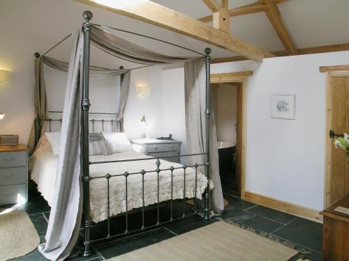 ein Schlafzimmer mit einem Himmelbett in einem Zimmer in der Unterkunft The Cart House in Milford