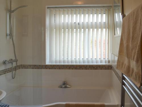 a bathroom with a bath tub and a window at Dart Corner in Bovey Tracey