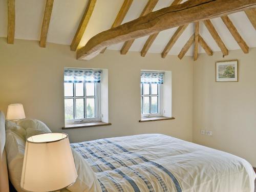 a bedroom with a bed and two windows at Honeypot Cottage in Saint Cross