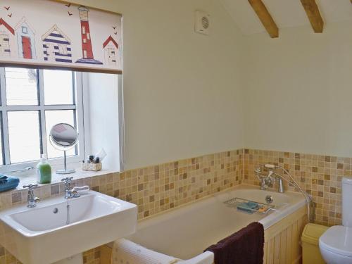 a bathroom with a sink and a bath tub at Honeypot Cottage in Saint Cross