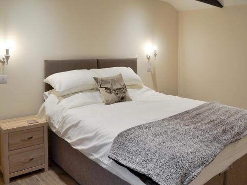 1 dormitorio con 1 cama grande con sábanas y almohadas blancas en Dairy Cottage, en Alkham