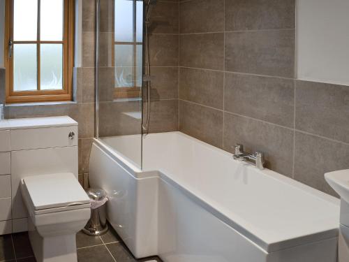 a bathroom with a white tub and a toilet at Dairy Cottage in Alkham