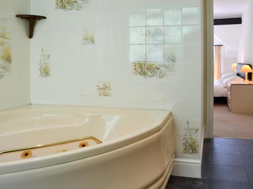 a white tub in a bathroom with a bedroom at Cedar Rest in Llanaber