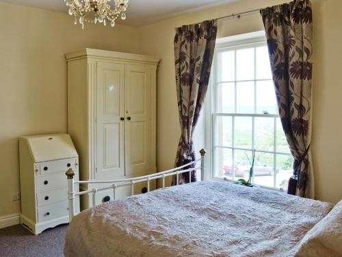 a bedroom with a bed and a window at Granary Cottage in Penrhyn Bay