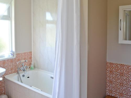 a bathroom with a tub and a shower curtain at Seafield in Llanrhyddlad