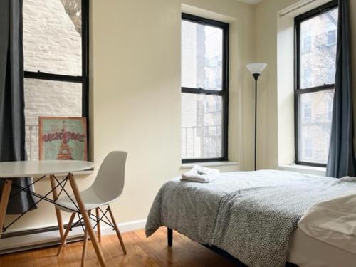 a bedroom with a bed and a table and windows at Budget Single Room Near Central Park in New York