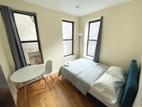 a bedroom with a bed and a table and two windows at Budget Single Room Near Central Park in New York