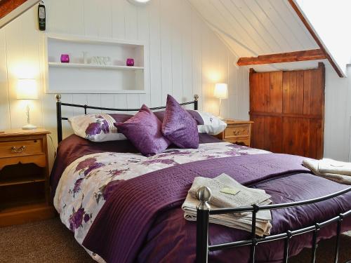 a bedroom with a bed with purple pillows at Hafan - 28081 in Llangwnadl