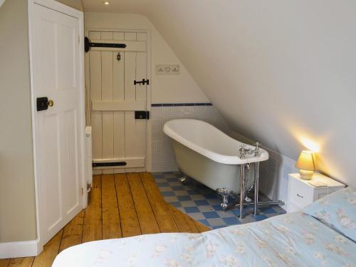 a attic bathroom with a tub and a bed at The Coach House The Old Rectory in Buckland St Mary