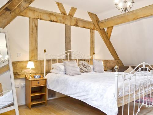 a bedroom with a white bed with wooden beams at The Olde Granary - E4298 in Halston