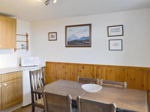 a dining room with a table and a kitchen at 3 Breckery in Staffin