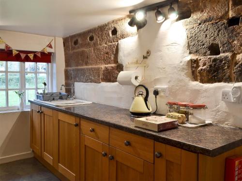 a kitchen with a stone wall and a counter with a lamp at Childe Of Hale Cottage - 27896 in Hale