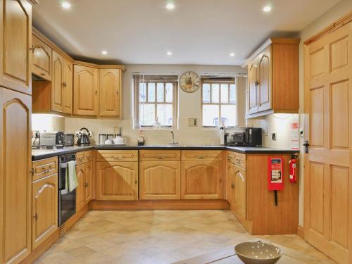 a large kitchen with wooden cabinets and appliances at The Olde Granary - E4298 in Halston