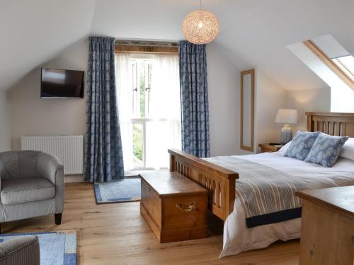 um quarto com uma cama, uma cadeira e uma janela em Paxton View Barn em Llanddarog