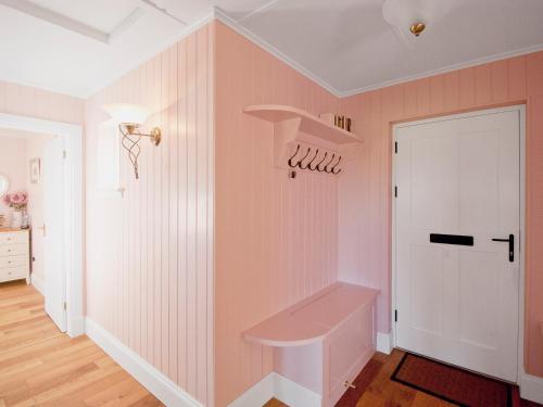 a kitchen with pink walls and a white door at Dunultach Cottage in Ronachan