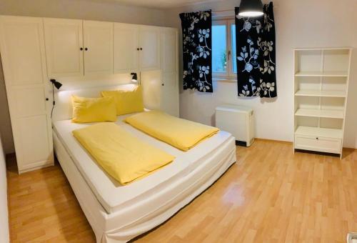 a white bed with yellow pillows in a bedroom at Bergurlaub Königsleiten in Königsleiten