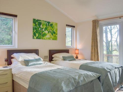 twee bedden in een slaapkamer met twee ramen bij Oak Lodge in Clatworthy