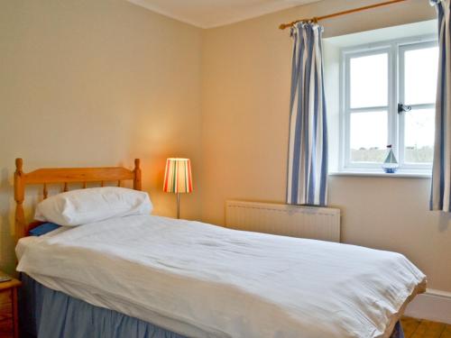 a bedroom with a large white bed with a window at The Pightl - 17627 in Castle Acre