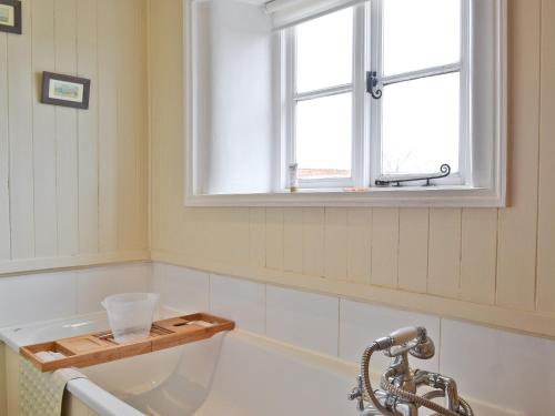 uma banheira na casa de banho com uma janela em The Pightl - 17627 em Castle Acre