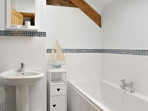 a white bathroom with a sink and a bath tub at Llofft Storws in Valley