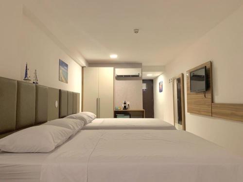 1 cama blanca grande en una habitación con TV en Beach Class Executive, en Recife