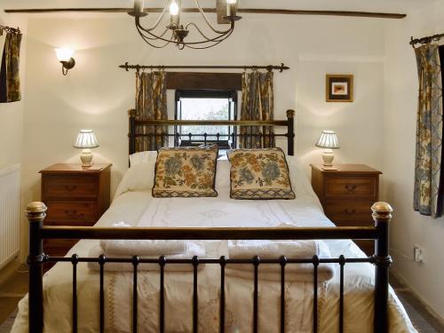 キャッスルトンにあるMushroom Cottageのベッドルーム1室(木製ベッド1台、ナイトスタンド2台付)