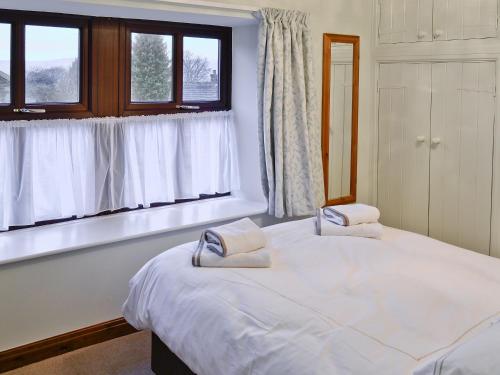 a bedroom with two beds and two windows at Sycamore Cottage in Grassington