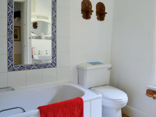 a bathroom with a tub and a toilet and a mirror at Driftcombe Farmhouse in Bisley
