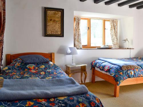 a bedroom with two beds and a window at Driftcombe Farmhouse in Bisley