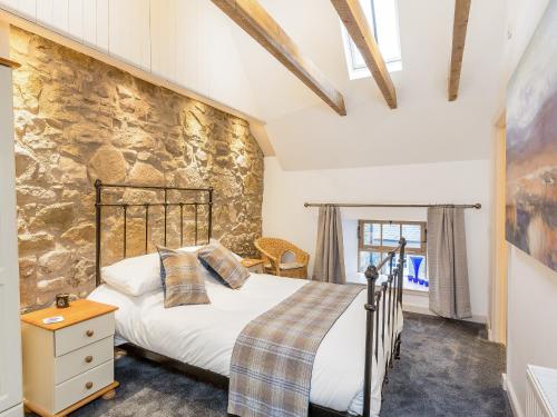 a bedroom with a bed and a stone wall at The Hayloft in Blitterlees