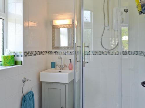a white bathroom with a sink and a shower at Mill Cottage in Stillington