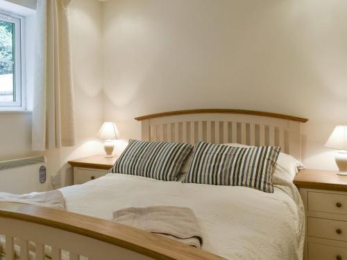 een slaapkamer met een bed met gestreepte kussens en 2 lampen bij Endless Summer Cottage in Camelford