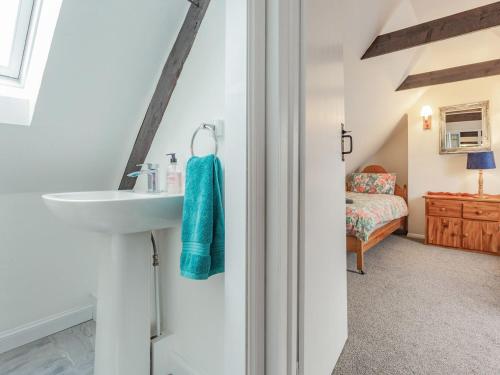 a bathroom with a sink and a bedroom at Seathrift Cottage in Ardersier