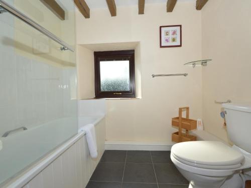 a bathroom with a toilet and a tub and a window at Buzzards View in Kingswear