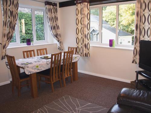 uma sala de jantar com mesa, cadeiras e janelas em Kingfisher - 30788 em Swimbridge