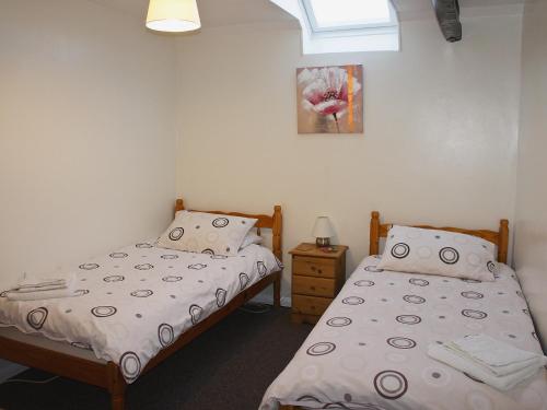 a bedroom with two beds and a picture on the wall at Kingfisher - 30788 in Swimbridge